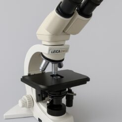 Ein beiges und schwarzes Leica DMLS Mikroskop mit zwei Okularen, einem Revolver mit drei Objektiven, einem quadratischen Probentisch und einem groben und feinen Fokussierknopf.